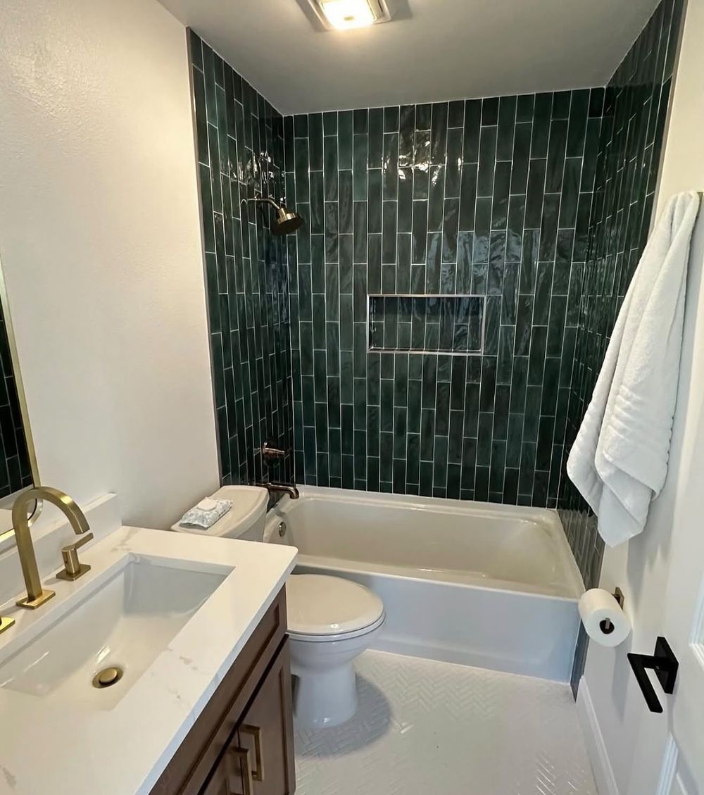 Green tile tub surround with gold vanity faucet